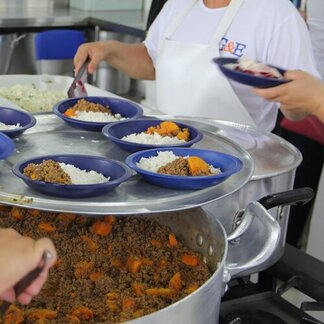 A container of food. On the lid there are individual plates with rice and venetables on