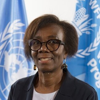 Joyce Luma, Assistant Executive Director a.i, Partnerships and Innovation, photographed in front of WFP and United Nations flags.