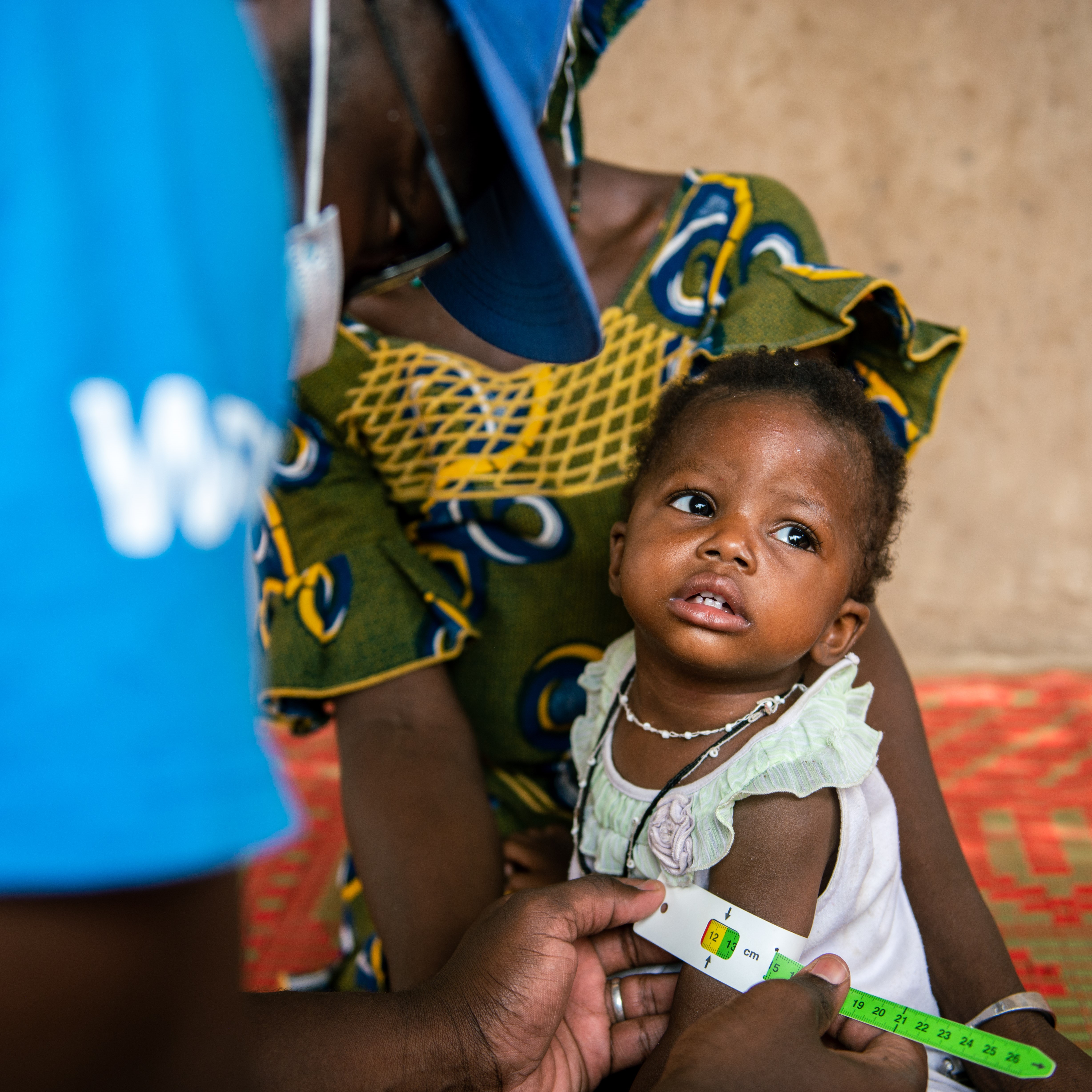 A WFP staff member measures Kadidia's arm, who is undergoing malnutrition treatment, during a visit to her home in Nioro, Mali, on 2 June 2022.